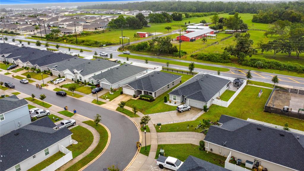 An aerial view shows a suburban neighborhood with single-family homes, paved streets, and green fields — 190 POLERMO AVENUE, ST CLOUD, FL