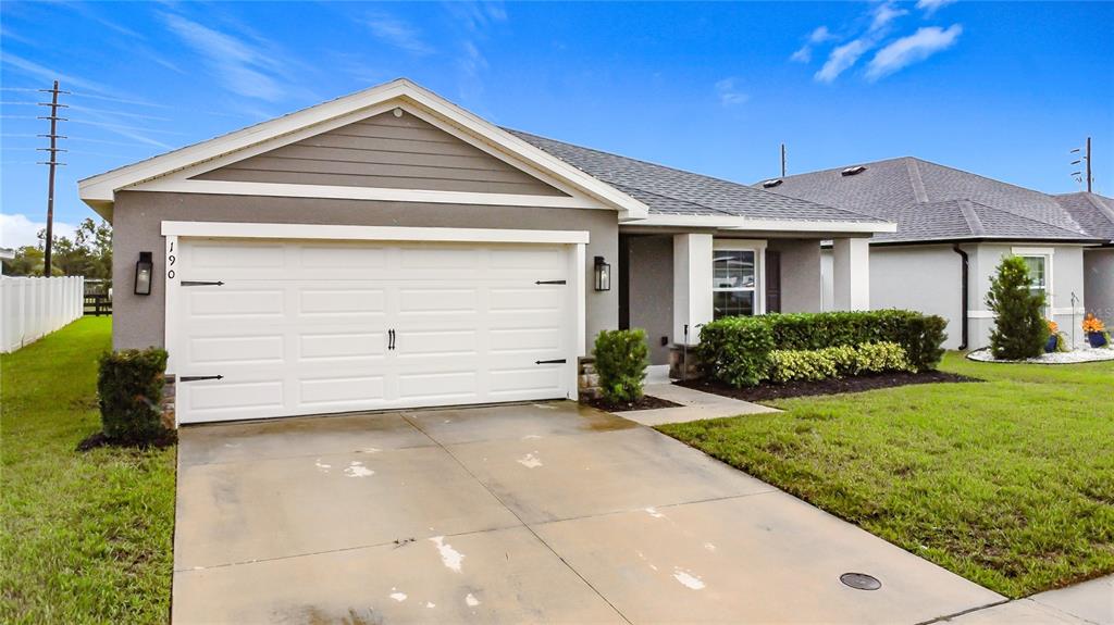 A single-story house with a white garage door, gray siding, and a concrete driveway — 190 POLERMO AVENUE, ST CLOUD, FL