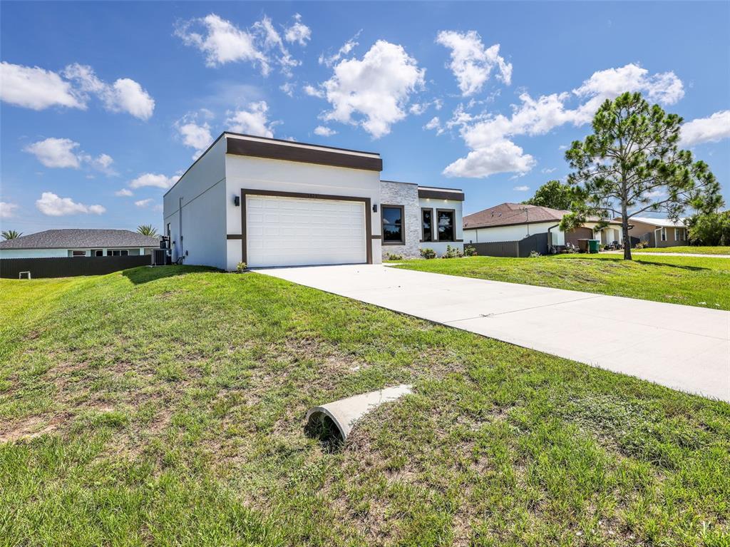 A modern, white single-story house with a flat roof and a concrete driveway — 1423 NW 20TH TERRACE, CAPE CORAL, FL