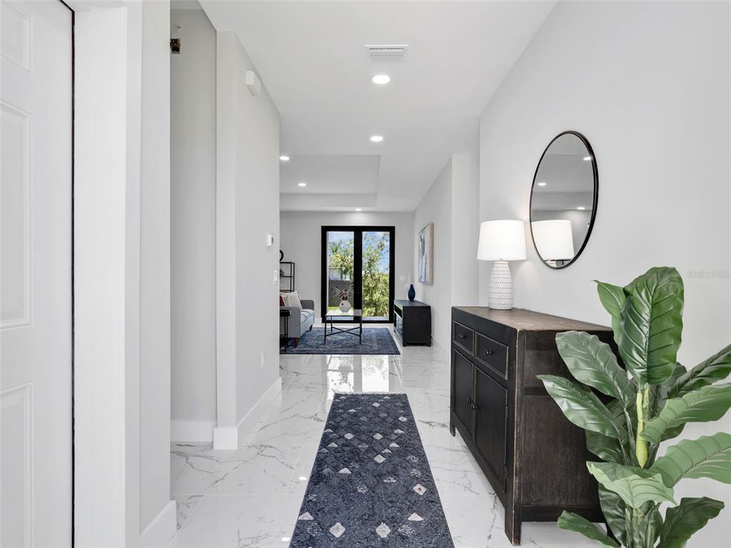 A bright hallway with white marble floors leads to a living area with glass doors — 1423 NW 20TH TERRACE, CAPE CORAL, FL