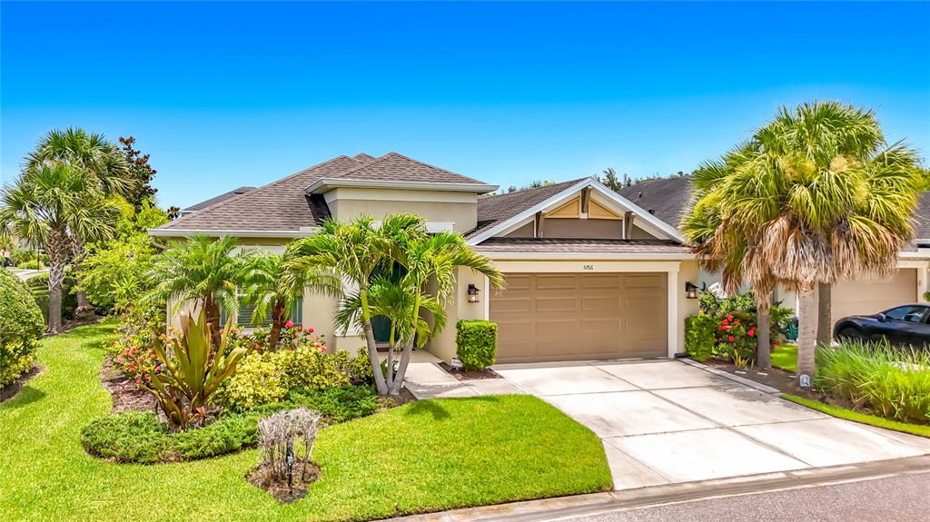 A single-story suburban house with a tan exterior, a two-car garage, and palm trees — 5766 MAYPOP CIR, SARASOTA, FL