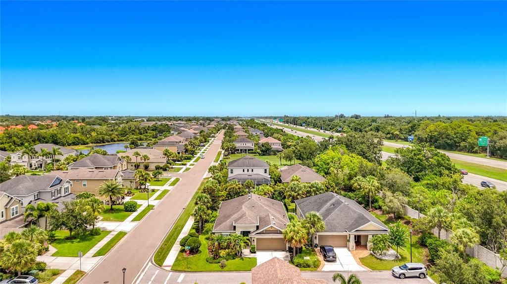 An aerial view shows a suburban neighborhood with houses, streets, and a nearby highway — 5766 MAYPOP CIR, SARASOTA, FL
