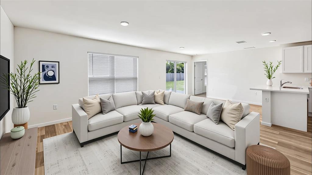 A modern living room features a large sectional sofa, a round coffee table, and wood flooring — 9715 N MITCHELLE DRIVE, DUNNELLON, FL