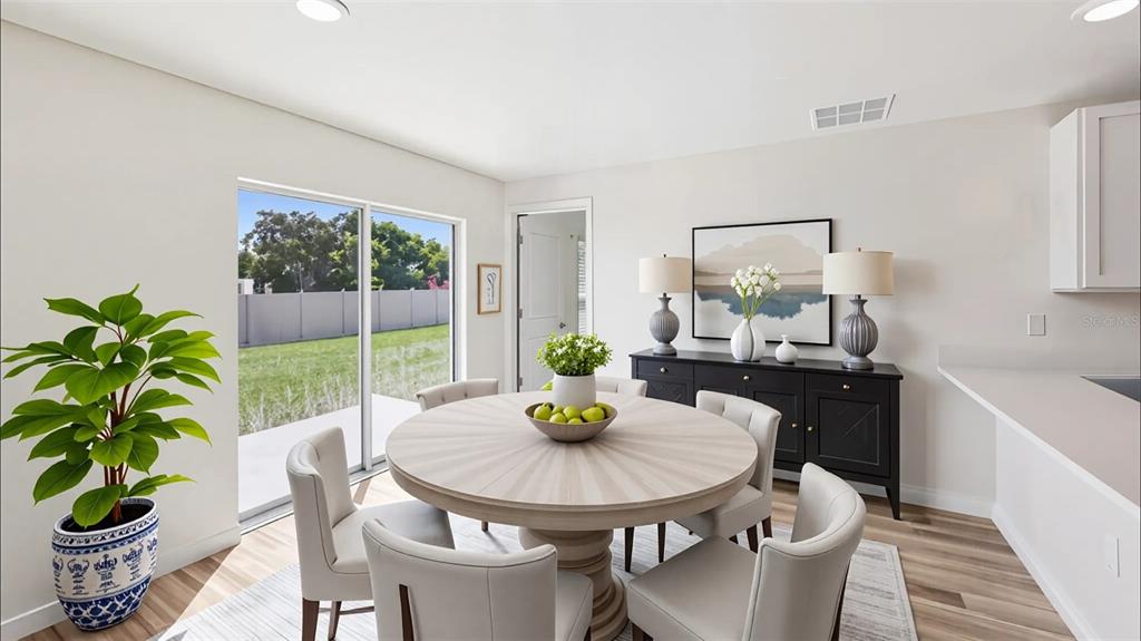 A dining room with a round table, four chairs, a black sideboard, and sliding glass doors — 9715 N MITCHELLE DRIVE, DUNNELLON, FL