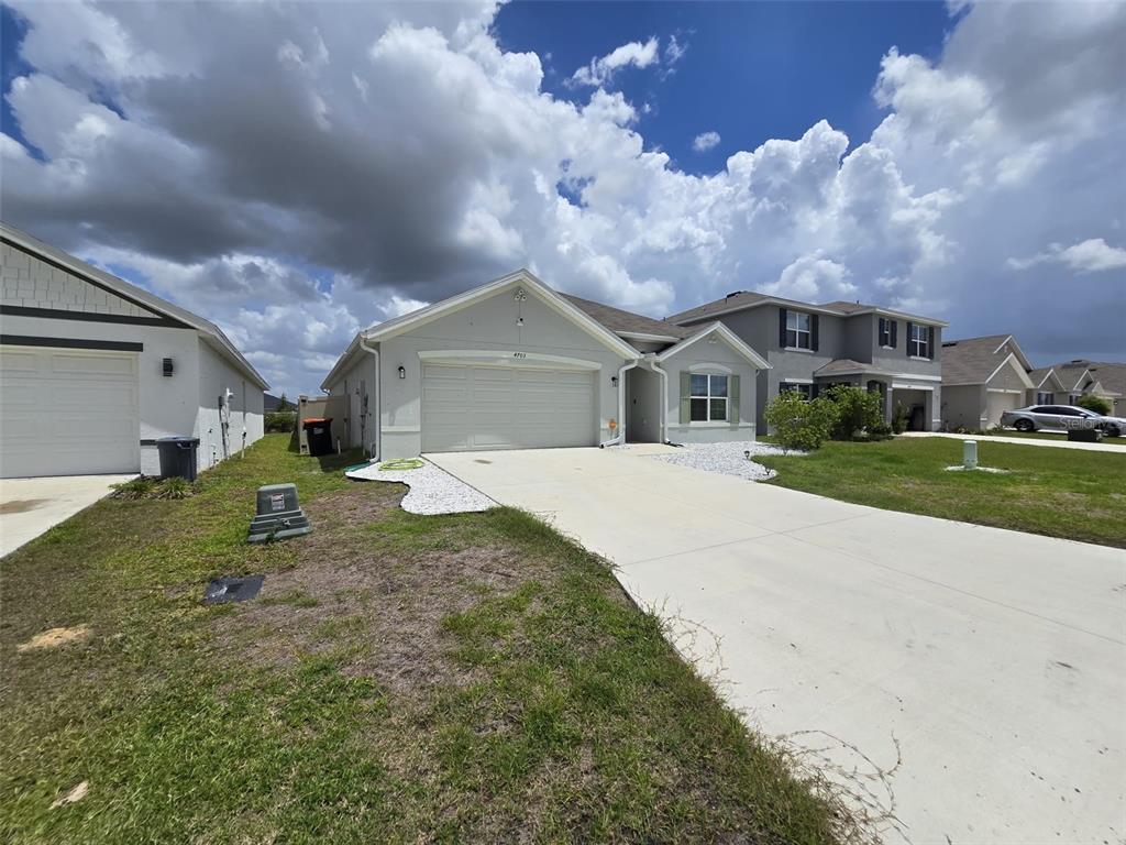 A single-story suburban house with a light-colored stucco exterior and a concrete driveway — 4703 SW 85TH PLACE, OCALA, FL