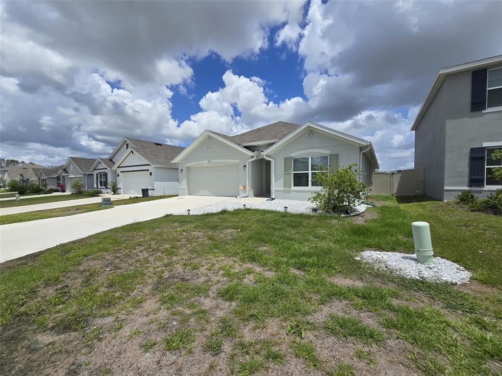 A single-story suburban house with a light-colored exterior, a two-car garage, and a lawn — 4703 SW 85TH PLACE, OCALA, FL