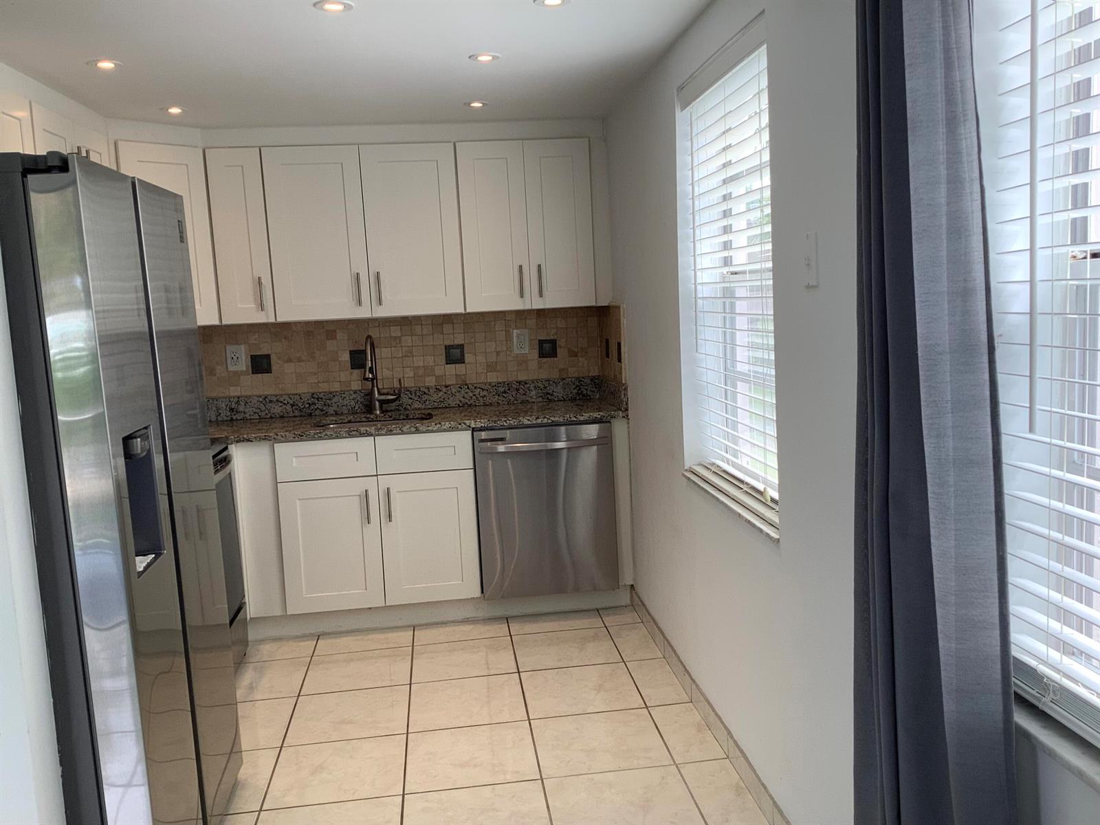 A kitchen with white cabinets, stainless steel appliances, granite countertops, and tiled flooring — 794 Normandy Q, Delray Beach FL 33484, DELRAY BEACH, FL