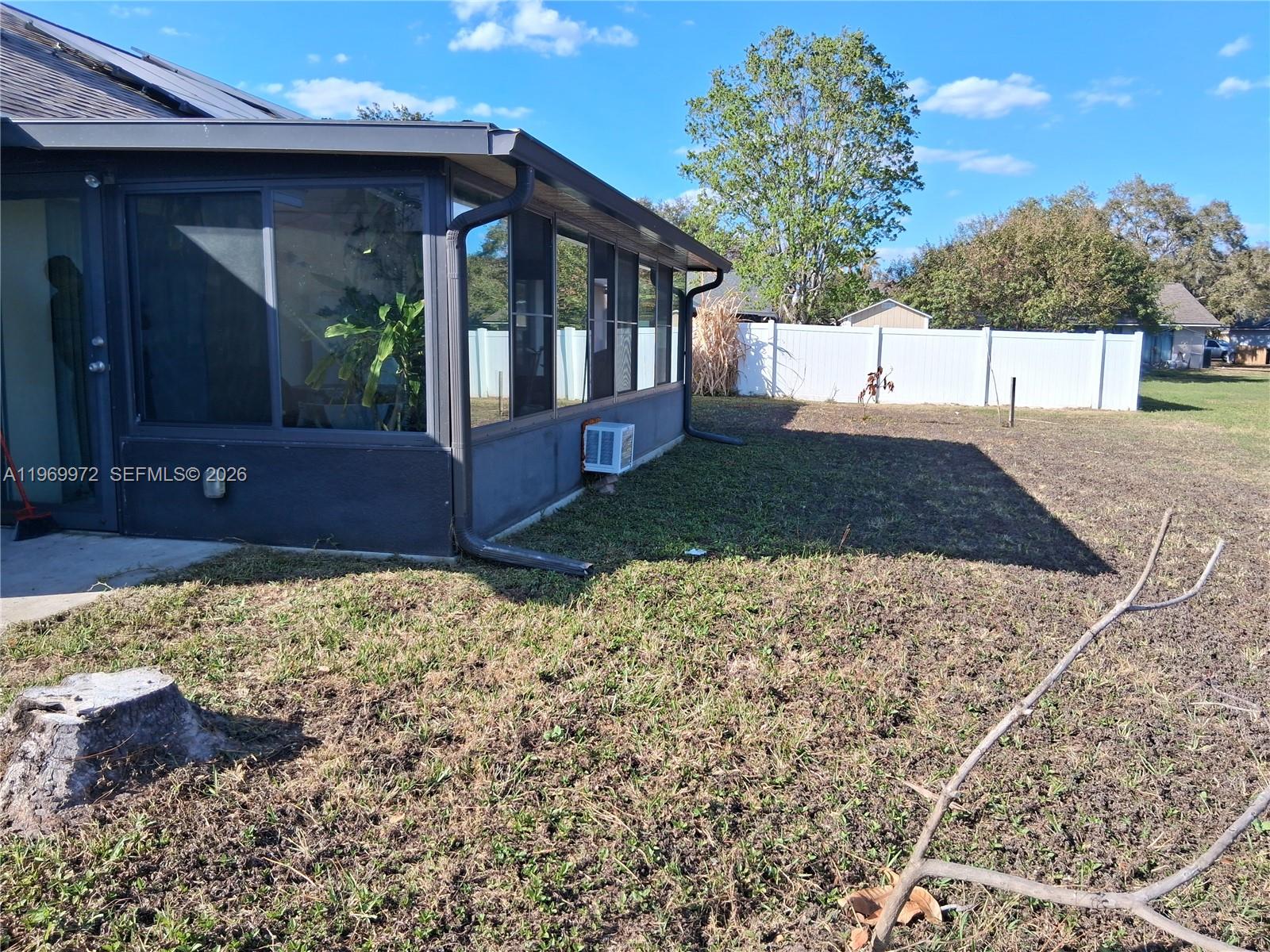 A dark-painted sunroom with large windows sits in a backyard next to a white fence — OTHER CITY - IN THE STATE OF FLORIDA, FL