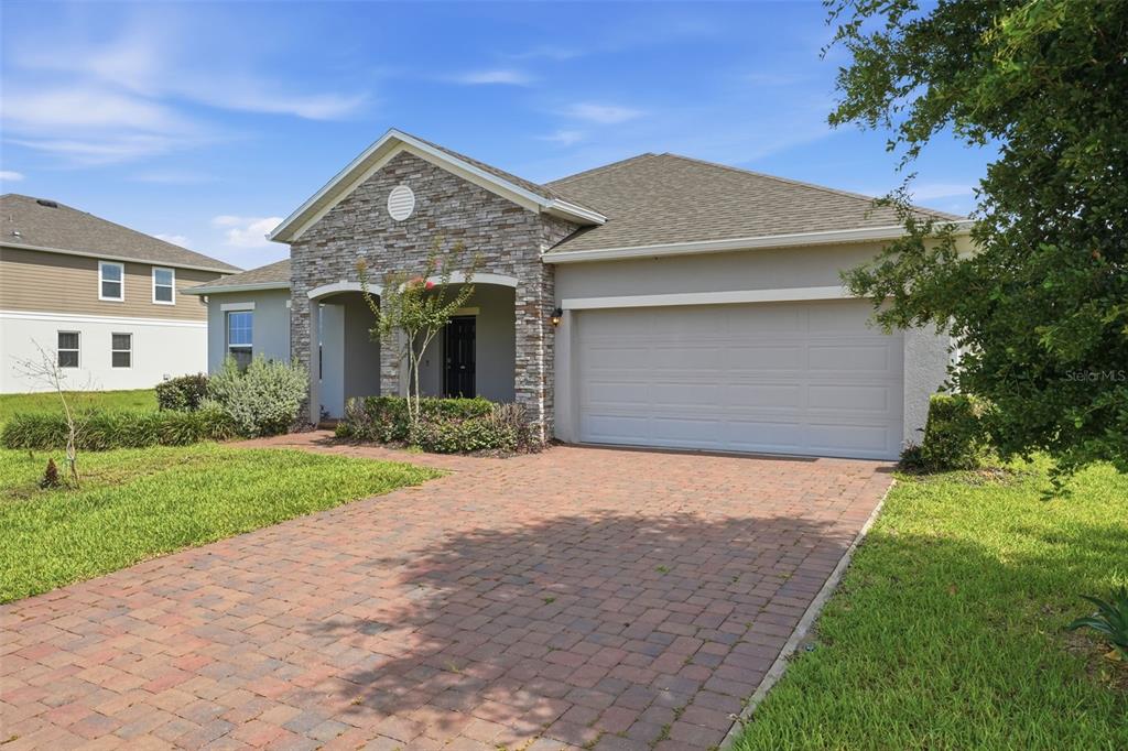 A single-story house with a stone facade, a two-car garage, and a brick paver driveway — 2524 CARRIAGE POINTE LOOP, APOPKA, FL