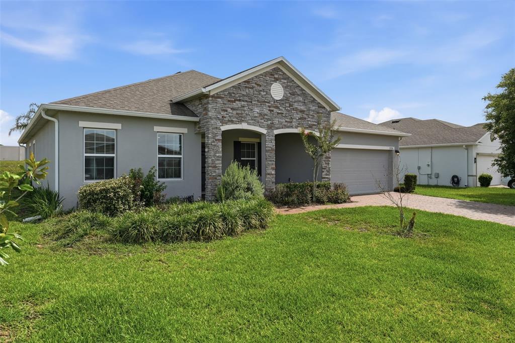 A single-story house with a stone facade, gray stucco walls, and a paved driveway — 2524 CARRIAGE POINTE LOOP, APOPKA, FL