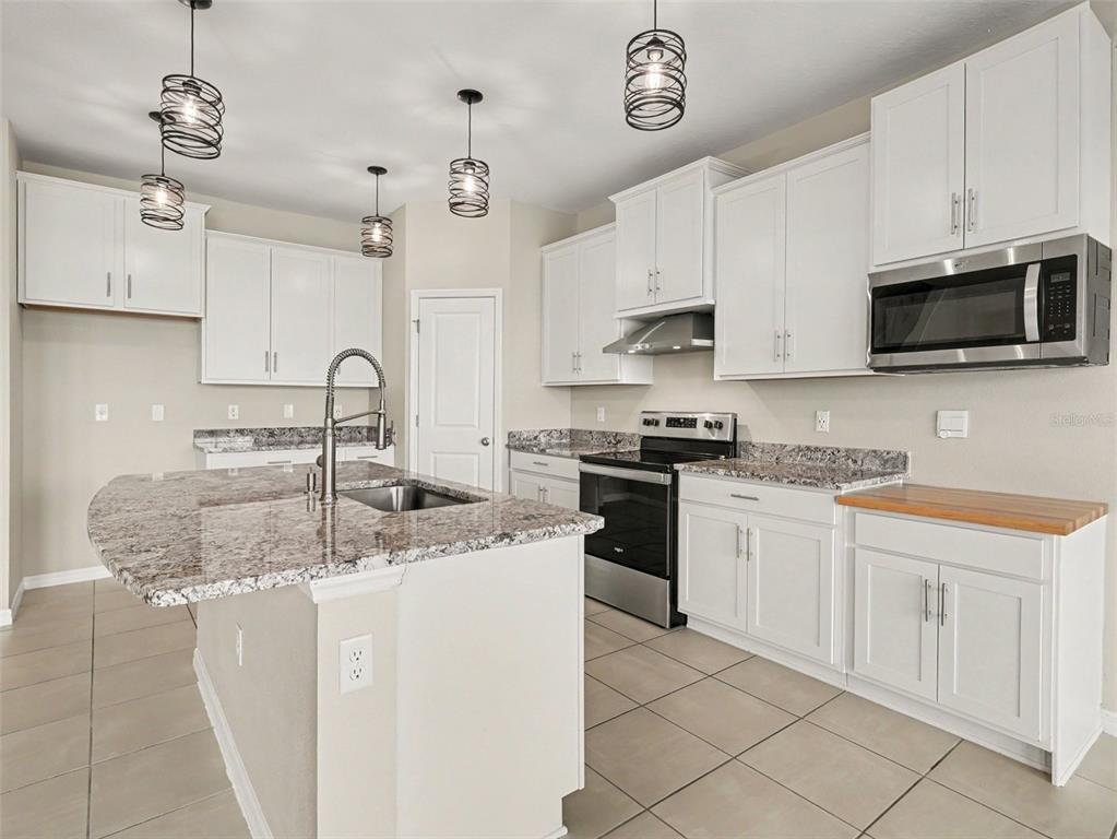 A kitchen with white cabinets, granite countertops, a center island, and stainless steel appliances — 1167 OCEAN SPRAY DRIVE, RUSKIN, FL