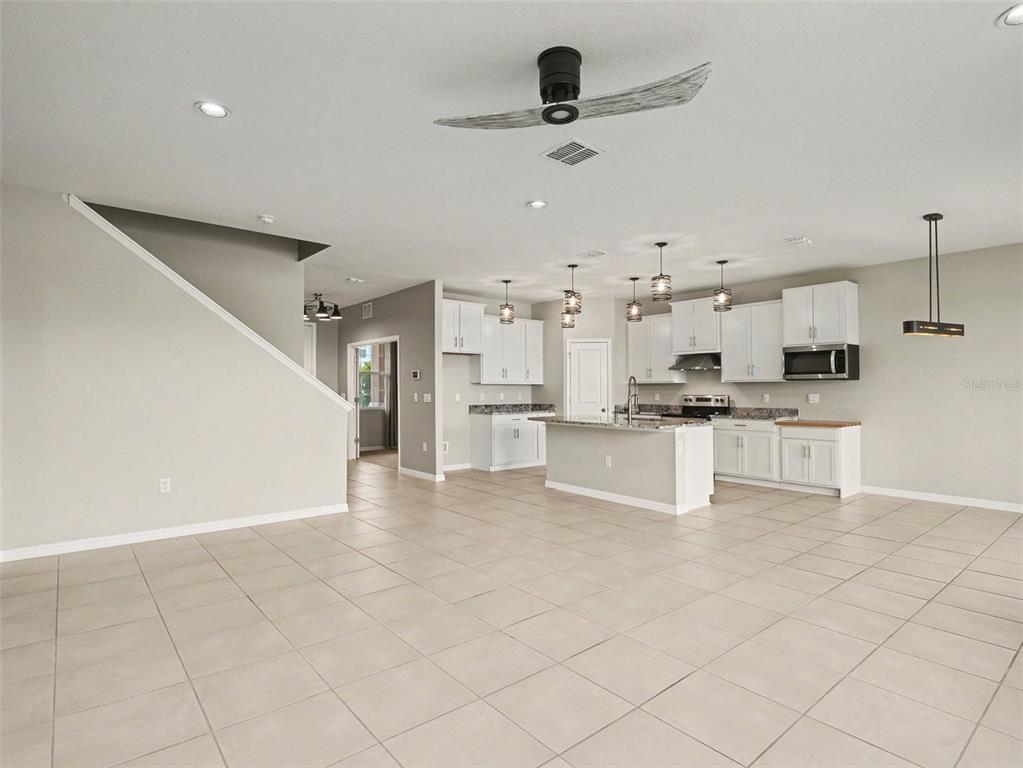 An open-concept kitchen features white cabinetry, a central island, and light-colored tile flooring — 1167 OCEAN SPRAY DRIVE, RUSKIN, FL