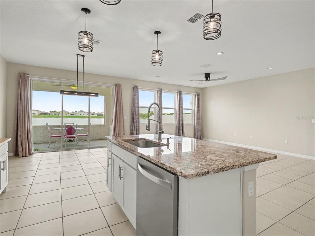A kitchen island with a granite countertop sits in a room with tile flooring and windows — 1167 OCEAN SPRAY DRIVE, RUSKIN, FL