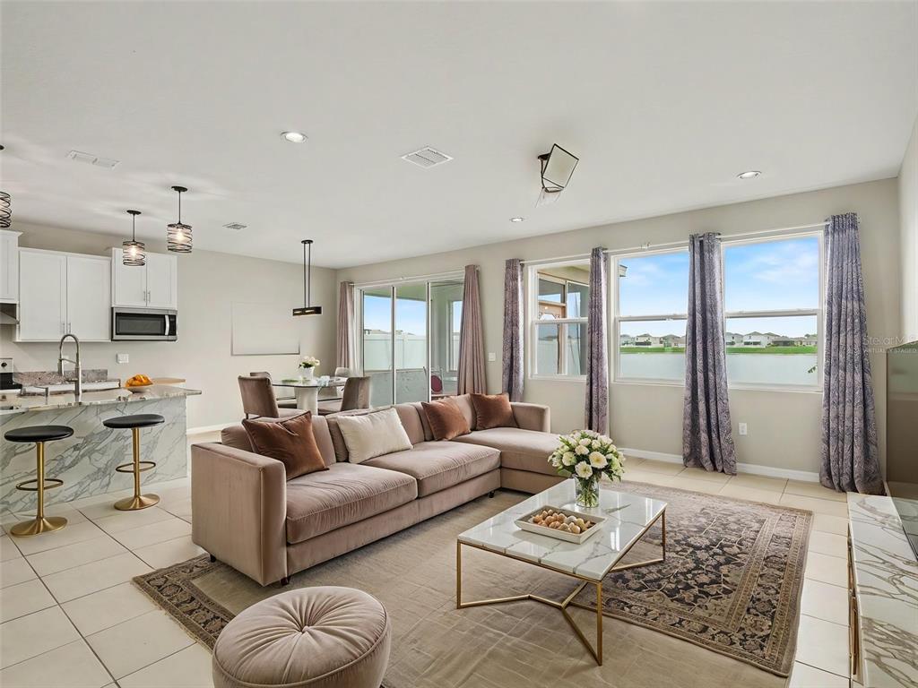 An open-concept living room and kitchen with a sectional sofa, marble island, and lake view — 1167 OCEAN SPRAY DRIVE, RUSKIN, FL