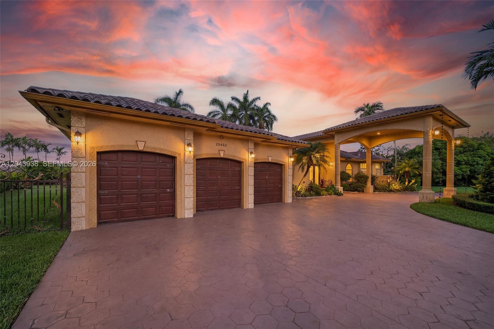 A three-car garage and a covered porte-cochère are attached to a house at sunset — 29482 SW 193rd Ct, Homestead FL 33030, HOMESTEAD, FL