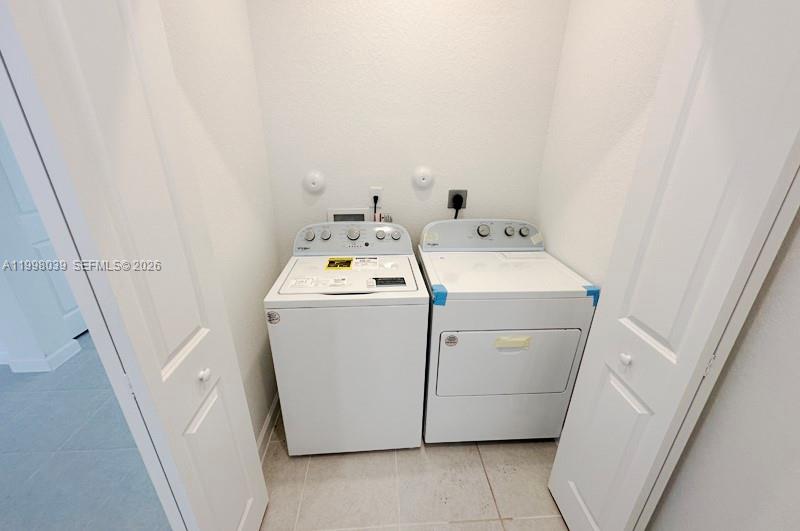 A laundry closet contains a white top-loading washing machine and a matching clothes dryer — 12432 NW 23rd Ct, Miami FL 33167, MIAMI, FL