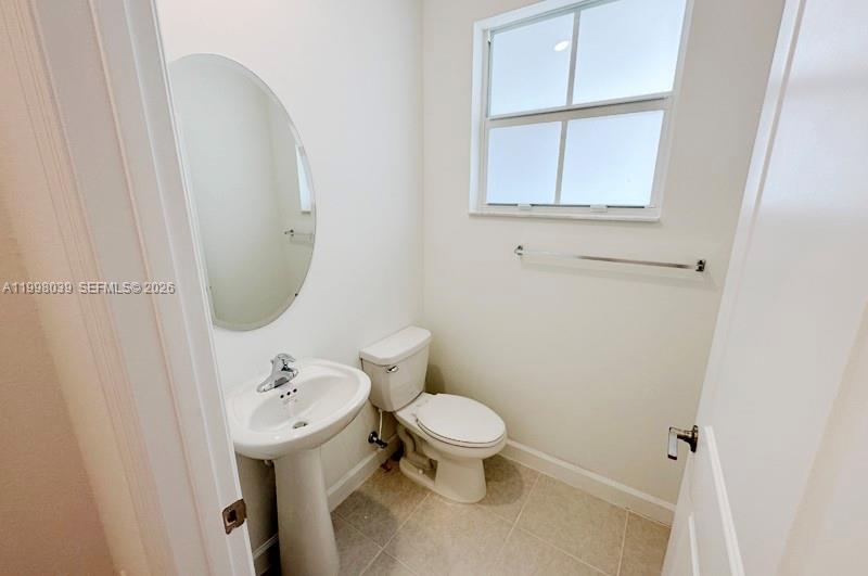 A small bathroom features a pedestal sink, a toilet, and a window with blinds — 12432 NW 23rd Ct, Miami FL 33167, MIAMI, FL