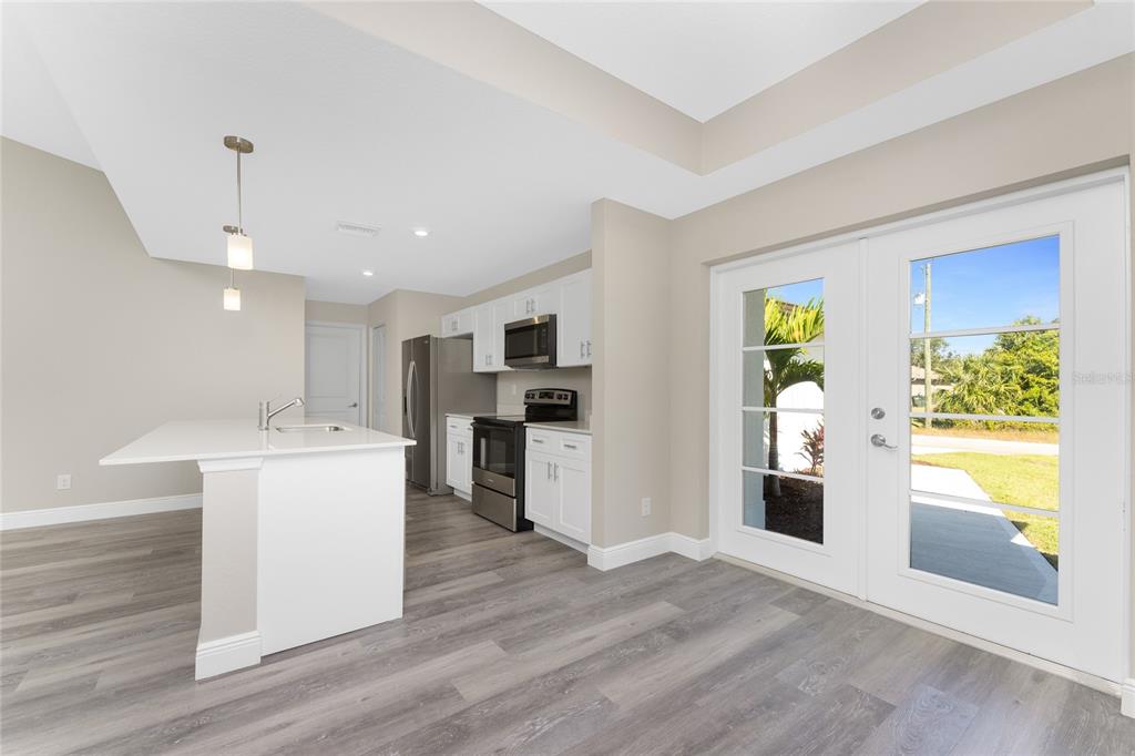 A kitchen with white cabinets, stainless steel appliances, a center island, and glass patio doors — 6397 FILBERT STREET, NORTH PORT, FL