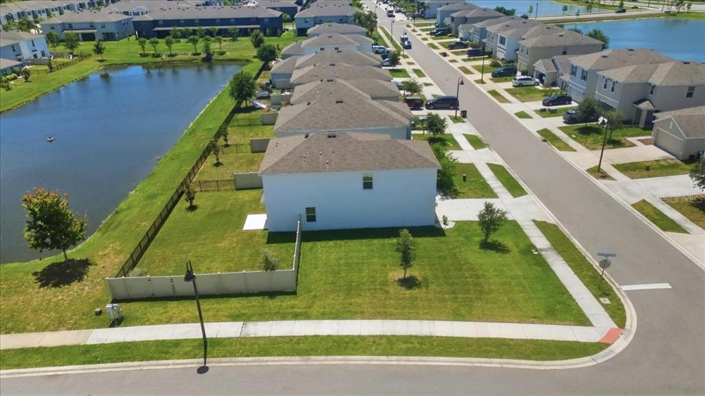 An aerial view shows a white house with a fenced yard next to a pond — 3126 SUNCOAST BLEND DRIVE, ODESSA, FL