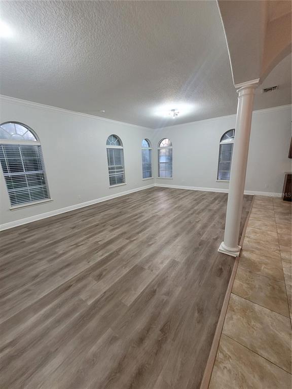 A spacious room features light gray walls, wood-look flooring, arched windows, and a white column — 1455 CATHERINE STREET, ORLANDO, FL