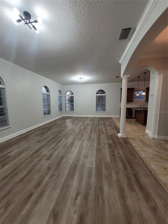 An open living area features wood-look flooring, arched windows, and a columned entryway to the kitchen — 1455 CATHERINE STREET, ORLANDO, FL