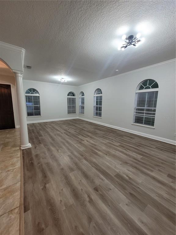 An empty room with light gray walls, wood-look flooring, arched windows, and a modern chandelier — 1455 CATHERINE STREET, ORLANDO, FL