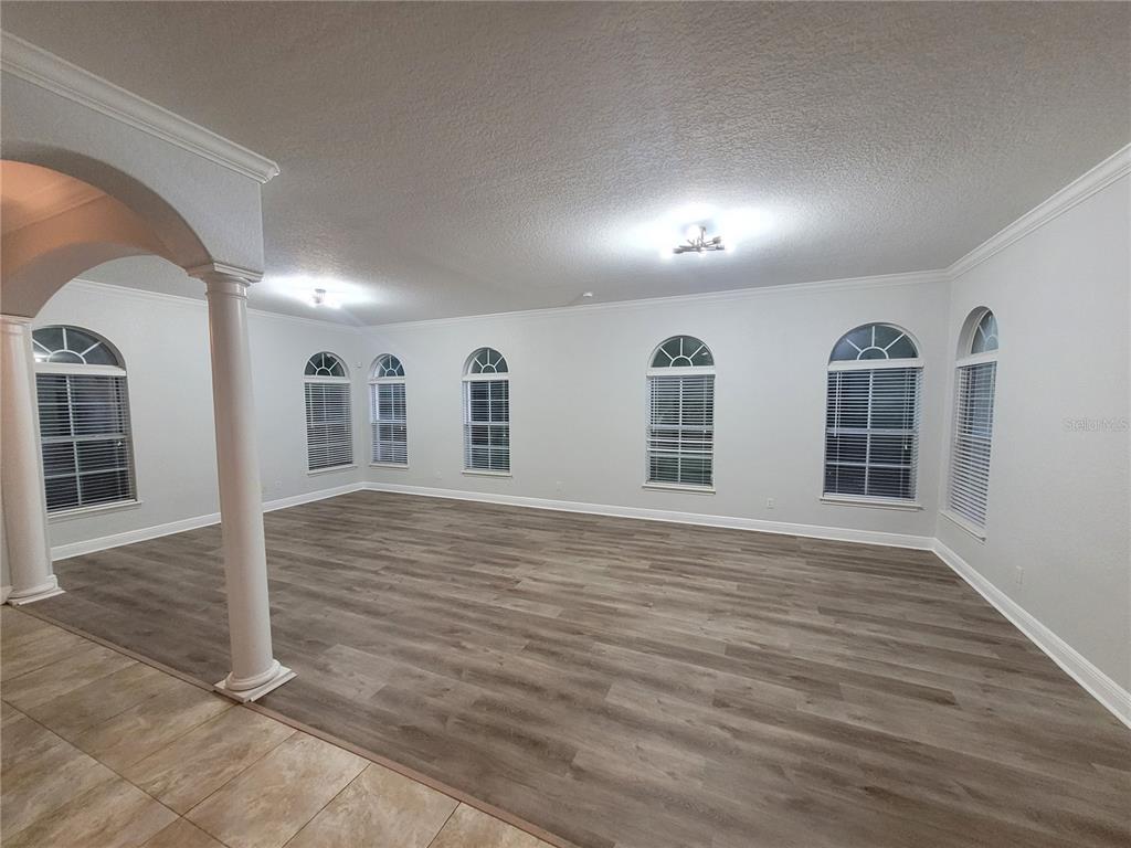An empty room features light wood-look flooring, white walls, arched windows, and a decorative column — 1455 CATHERINE STREET, ORLANDO, FL