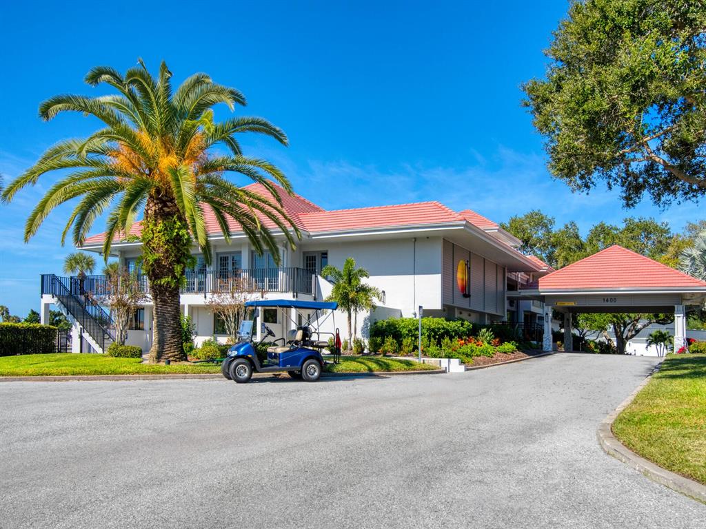 A two-story building with a red tile roof, a palm tree, and a golf cart — 1355 SOUTHBAY DRIVE, OSPREY, FL