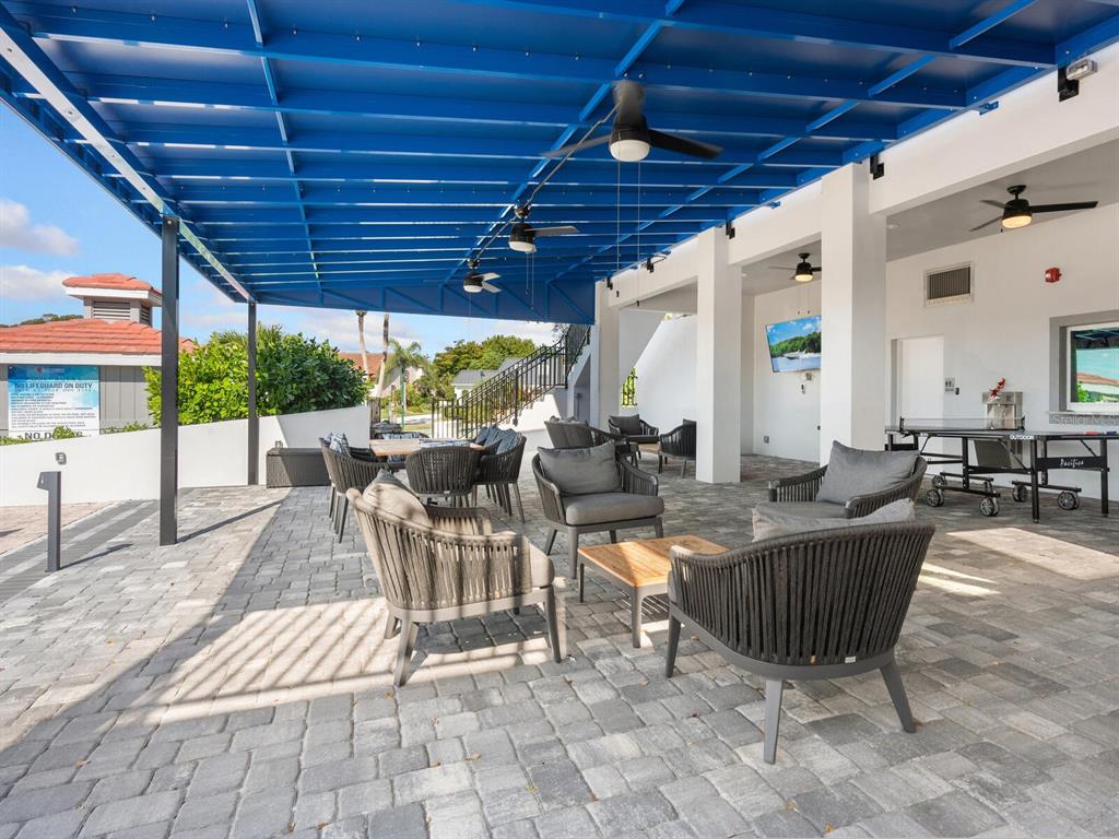 A covered outdoor patio features gray wicker seating, a ping pong table, and ceiling fans — 1355 SOUTHBAY DRIVE, OSPREY, FL