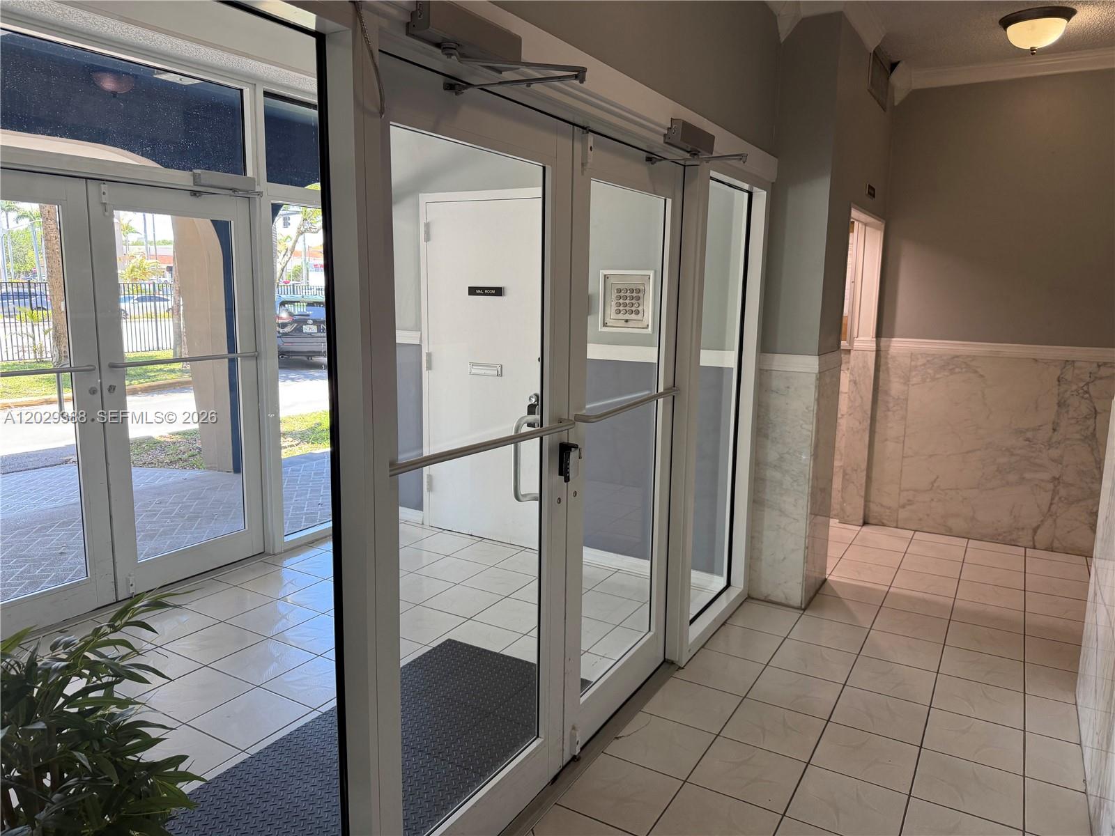 An interior entryway features glass double doors, white tile flooring, and marble wall accents — 501 E Dania Beach Blvd # 4D, Dania Beach FL 33004, DANIA BEACH, FL
