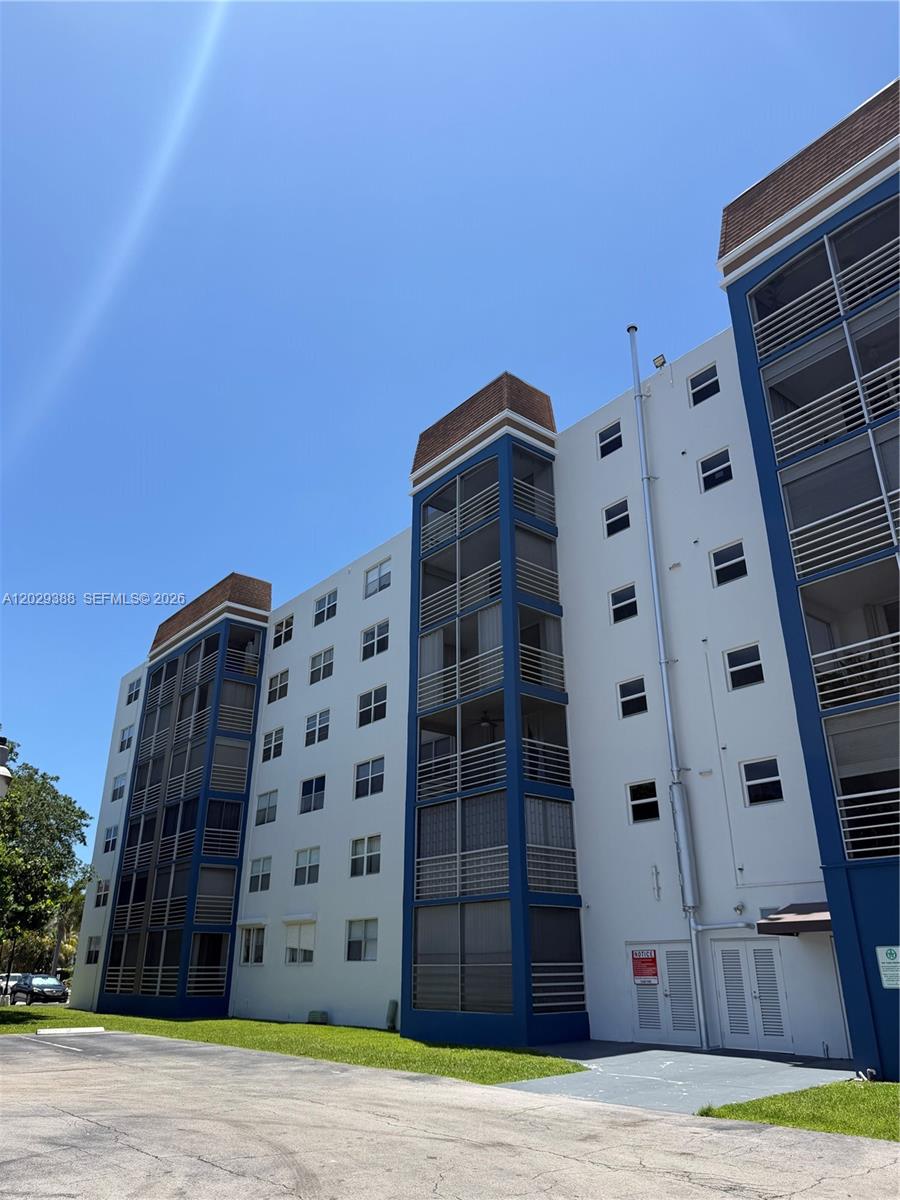 The exterior of a multi-story apartment building features white walls, blue trim, and screened balconies — 501 E Dania Beach Blvd # 4D, Dania Beach FL 33004, DANIA BEACH, FL