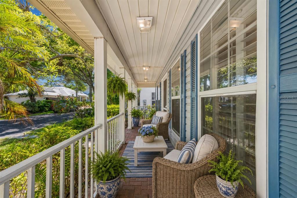 A covered porch features wicker furniture, a small table, and potted plants on brick flooring — 6414 23RD AVE DR W, BRADENTON, FL