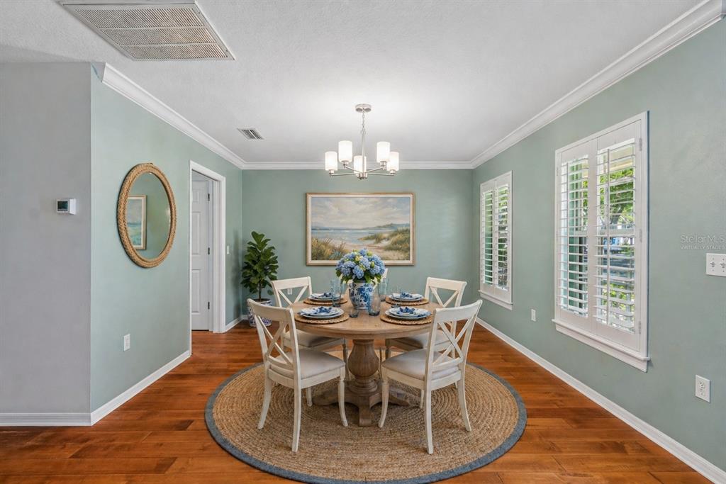 A dining room with a round wooden table, white chairs, and light blue walls — 6414 23RD AVE DR W, BRADENTON, FL