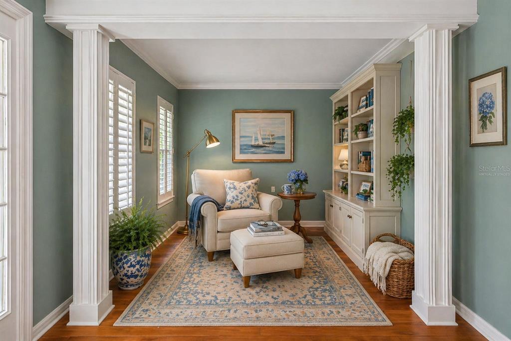 A cozy reading nook features a cream armchair, ottoman, built-in shelving, and blue-green walls — 6414 23RD AVE DR W, BRADENTON, FL