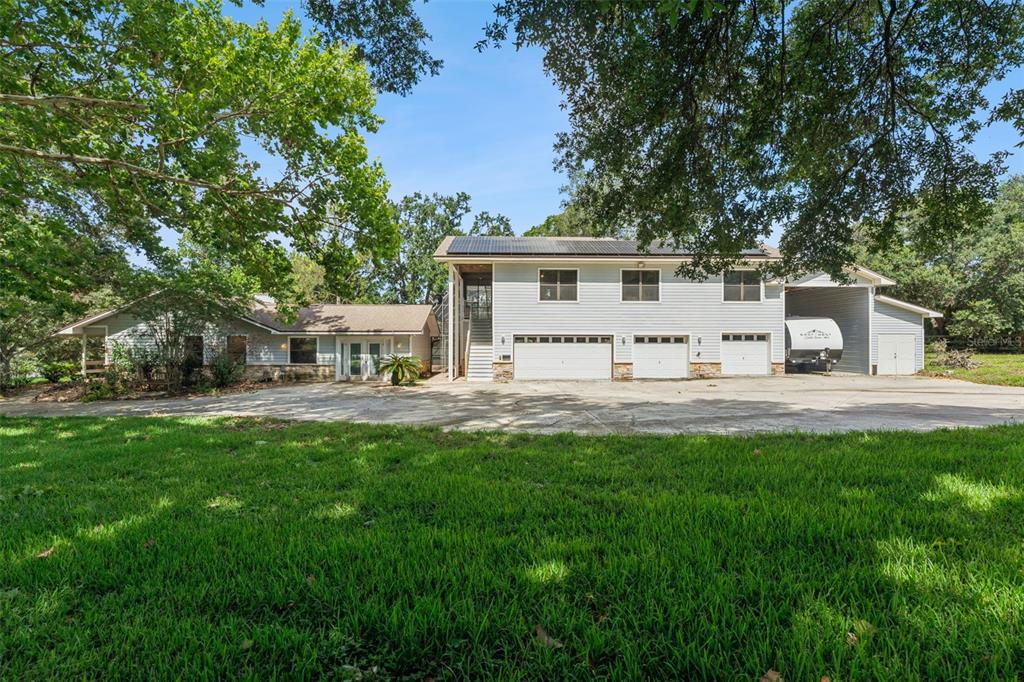 A two-story house with light siding, multiple garage bays, and a large concrete driveway — 15749 ARABIAN WAY, MONTVERDE, FL