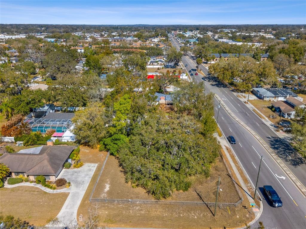 An aerial view shows a vacant, tree-covered lot situated next to a road and houses — 702 WESTWOOD DRIVE, BRANDON, FL