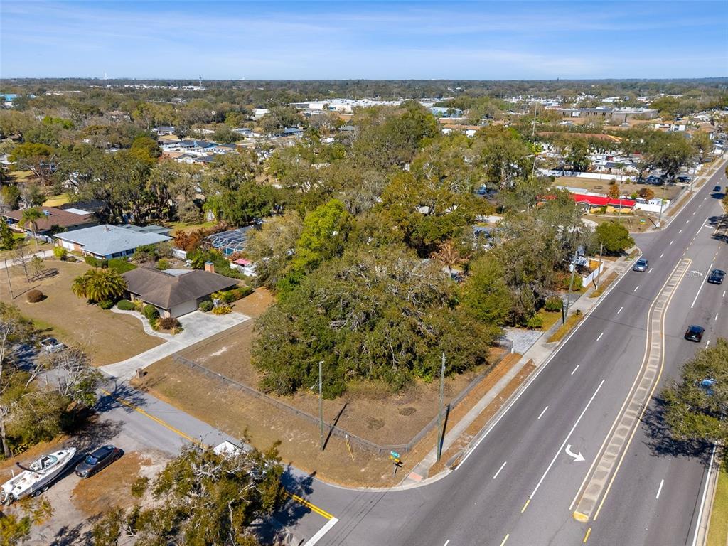 An aerial view shows a vacant, tree-covered corner lot adjacent to a multi-lane road — 702 WESTWOOD DRIVE, BRANDON, FL
