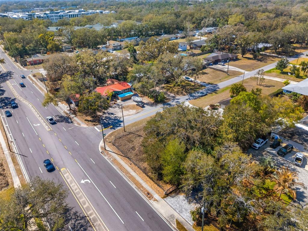 An aerial view shows a multi-lane road intersecting with a residential neighborhood featuring several houses — 702 WESTWOOD DRIVE, BRANDON, FL