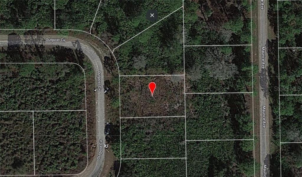 An aerial map view showing a vacant rectangular lot marked with a red pin — 1874 OUTPOST CIRCLE, LEHIGH ACRES, FL