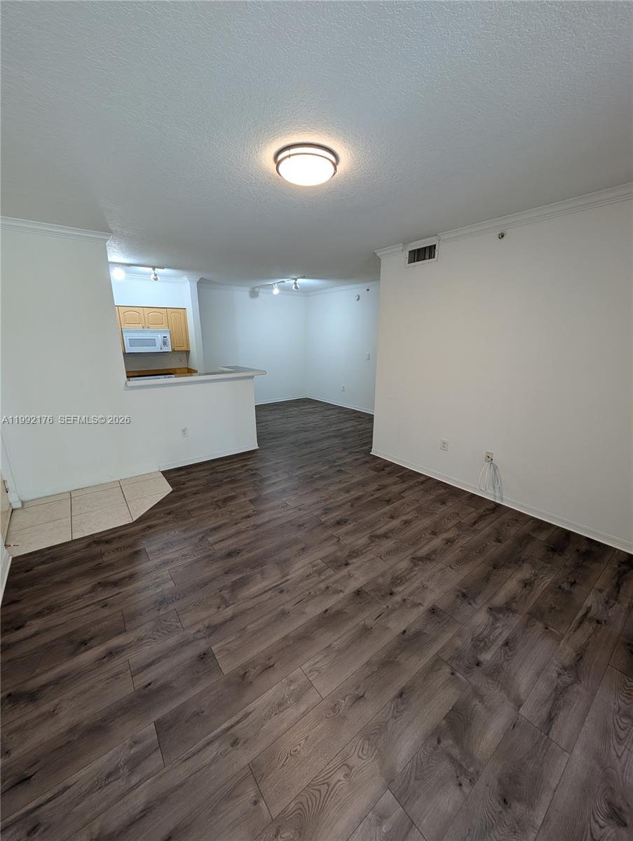 An open-concept living area features dark wood-look flooring and a kitchen with light wood cabinets — 6831 SW 44th St # 203, Miami FL 33155, MIAMI, FL