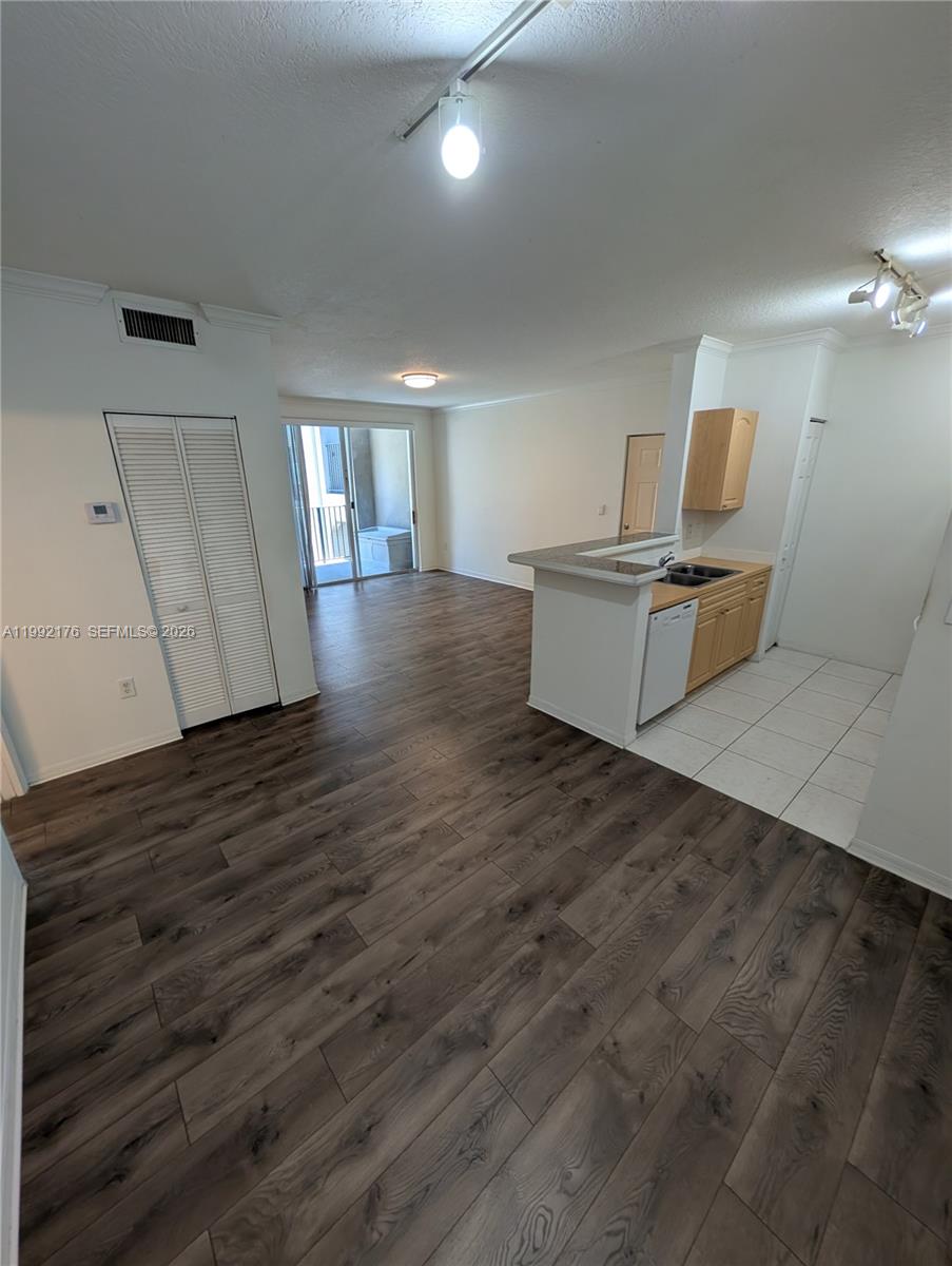 An open-concept living area features wood-look flooring, a kitchen with light cabinets, and a balcony — 6831 SW 44th St # 203, Miami FL 33155, MIAMI, FL