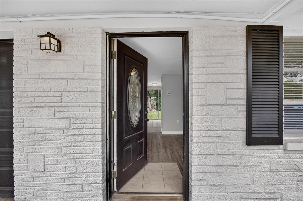 An open front door reveals a view into a home with wood-look flooring — 4540 IRENE LOOP, NEW PORT RICHEY, FL