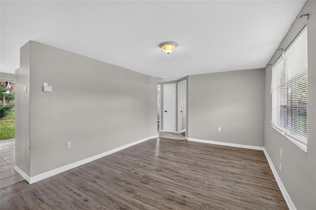 An empty living room with gray walls, wood-look flooring, and a window with blinds — 4540 IRENE LOOP, NEW PORT RICHEY, FL