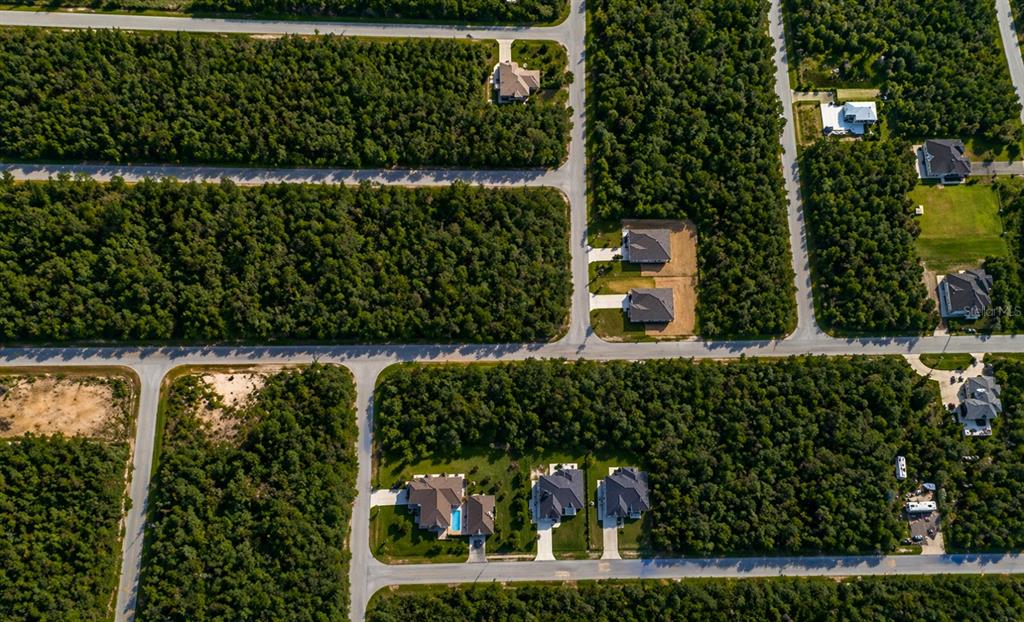 An aerial view shows several houses situated on large, wooded lots along paved roads — 157 HAMDEN STREET, PORT CHARLOTTE, FL