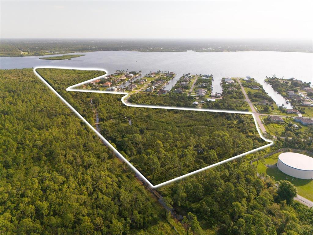 An aerial view shows a large, undeveloped wooded lot outlined in white near a waterway — 2925 VANCE TERRACE, PORT CHARLOTTE, FL