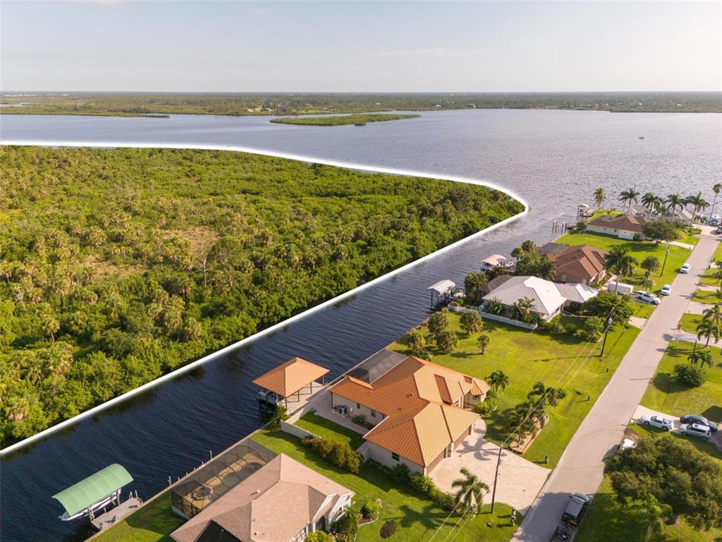 An aerial view shows a waterfront house with a boat dock beside a wooded area — 2925 VANCE TERRACE, PORT CHARLOTTE, FL