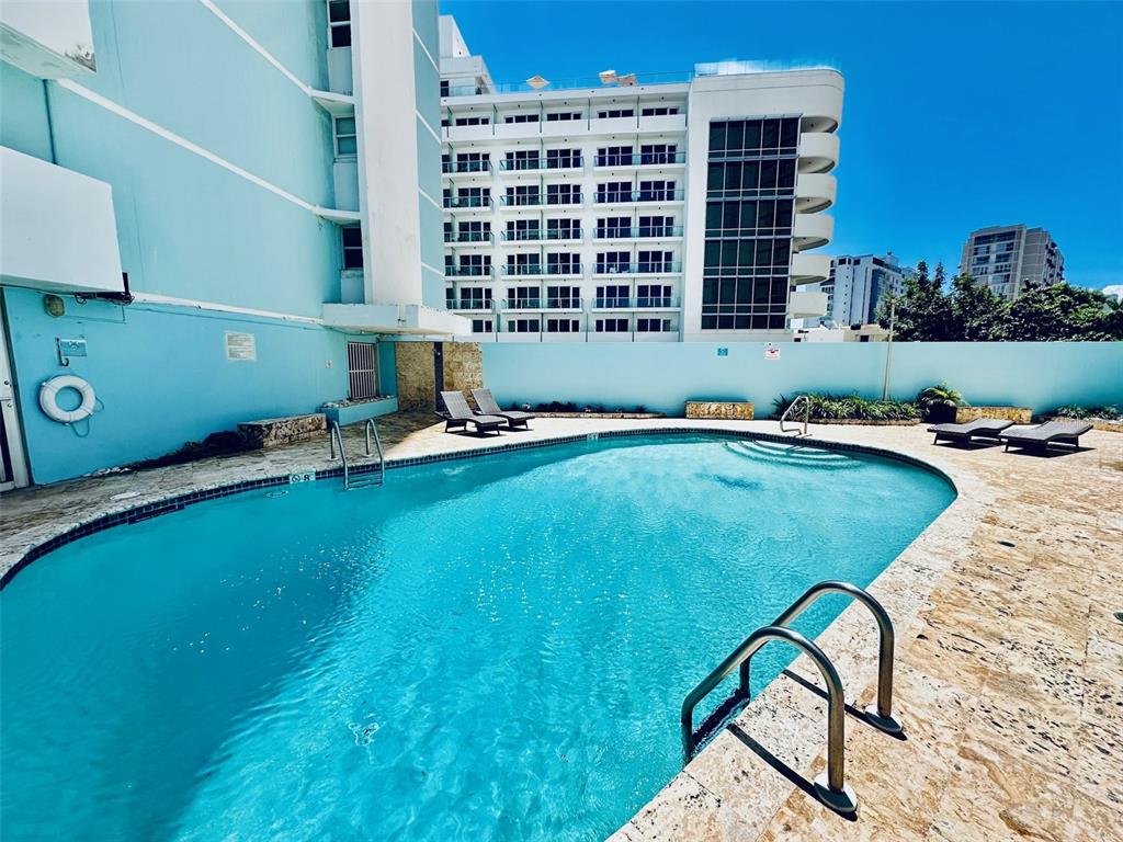 A swimming pool with lounge chairs sits in front of a multi-story building — 9 GARDENIA UNIT 4 C, CAROLINA, PR
