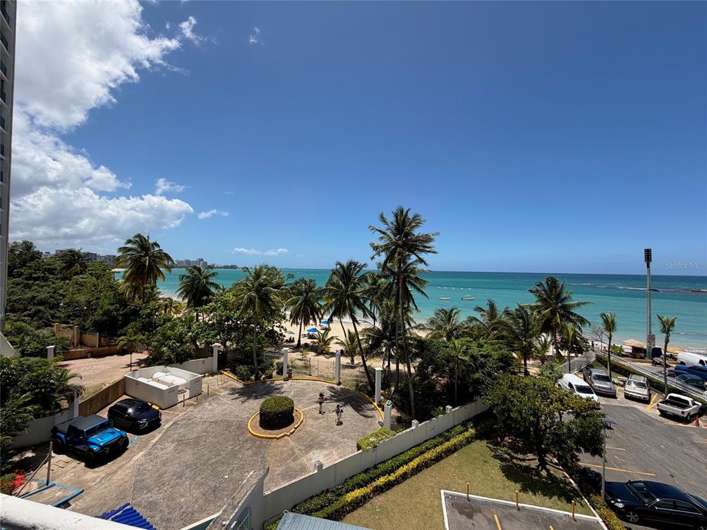 An elevated view shows a parking lot, palm trees, and a beach along the ocean — 9 GARDENIA UNIT 4 C, CAROLINA, PR