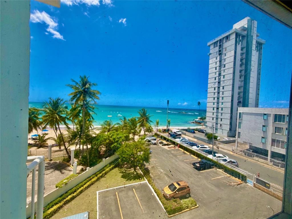 A high-angle view shows a beach, palm trees, a parking lot, and a tall building — 9 GARDENIA UNIT 4 C, CAROLINA, PR