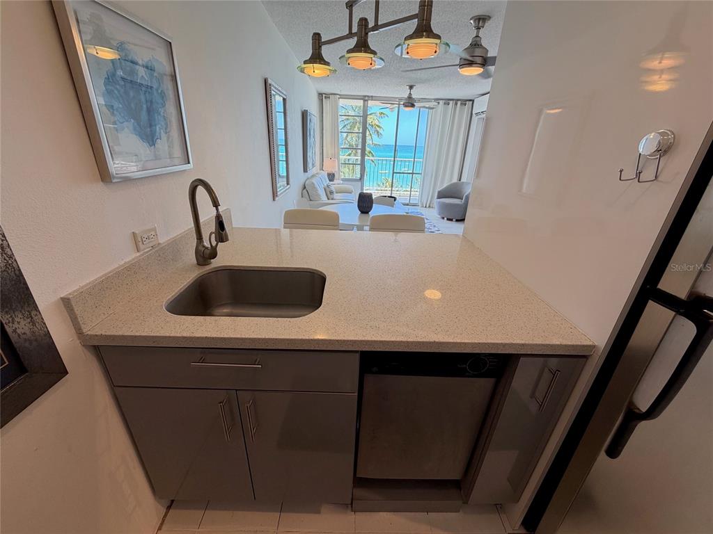 A kitchen sink and counter overlook a living area with a view of the ocean — 9 GARDENIA UNIT 4 C, CAROLINA, PR